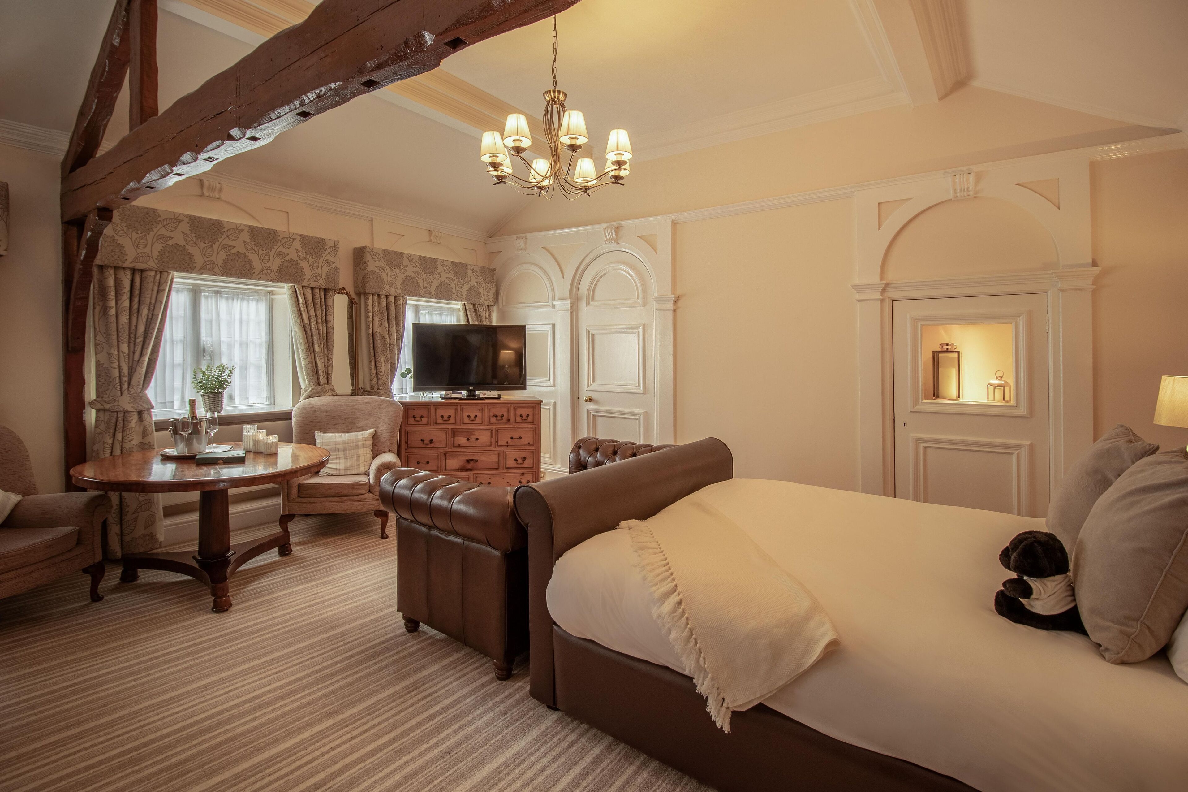 A cozy room with a large bed, a wooden coffee table, a leather sofa, and a television.