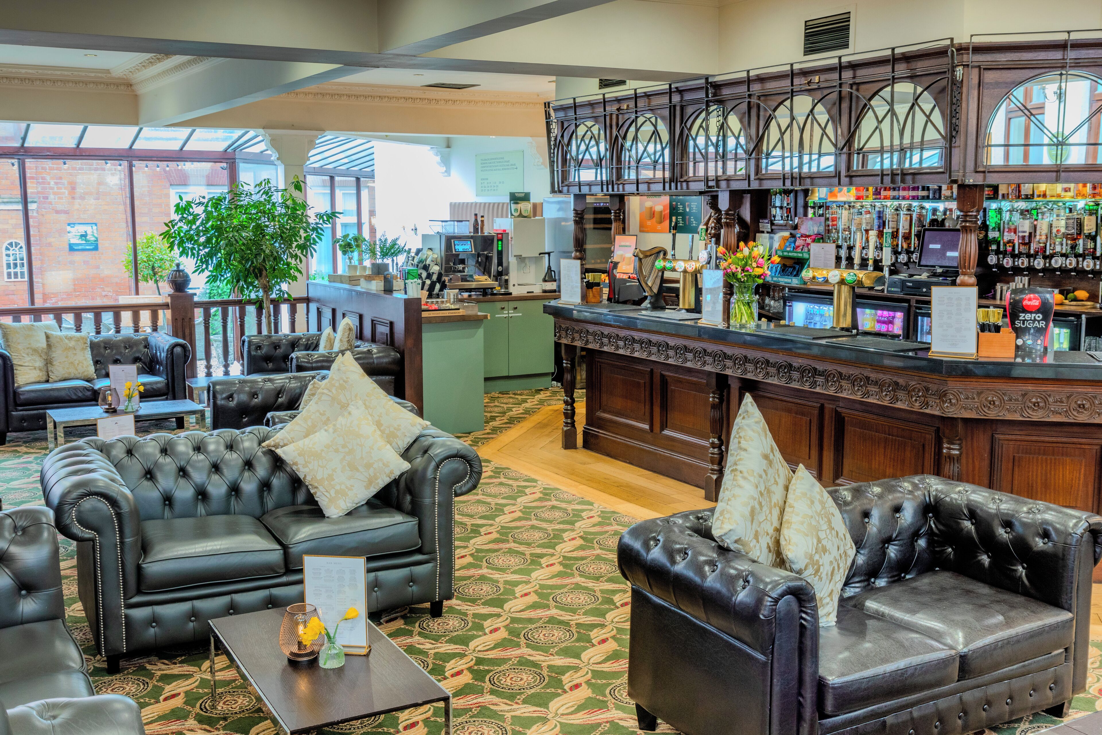 A hotel lobby with leather sofas, a bar area, and a view of a brick building.