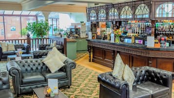 A hotel lobby with leather sofas, a bar area, and a view of a brick building.
