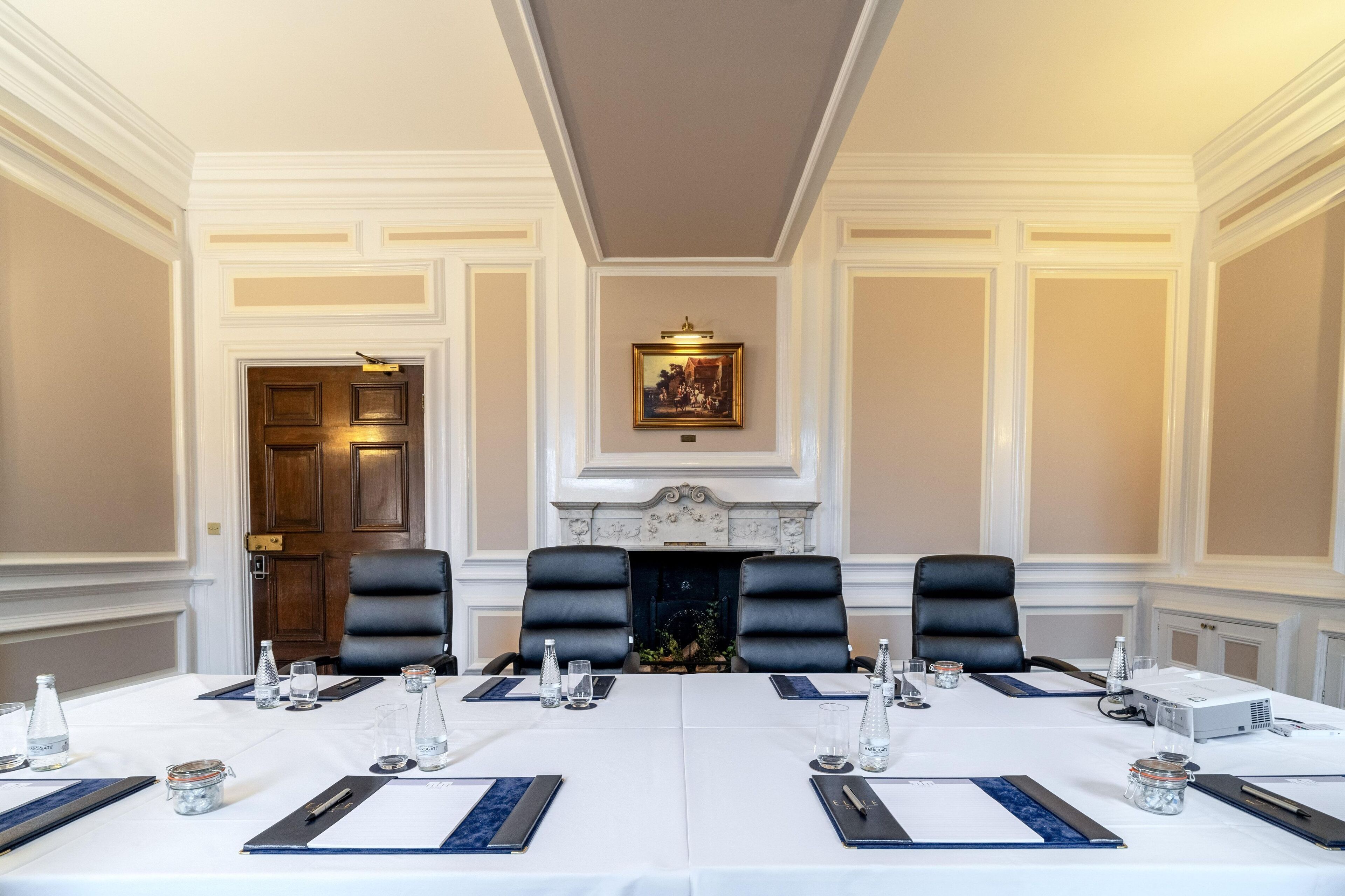A conference room with a long table, black leather chairs, and a fireplace.