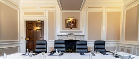 A conference room with a long table, black leather chairs, and a fireplace.