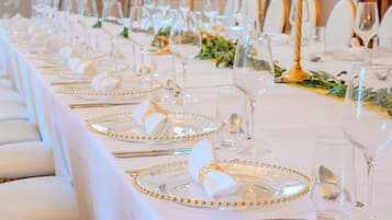 A long table set for a formal event with clear glassware, gold-rimmed plates, and neatly folded white napkins.