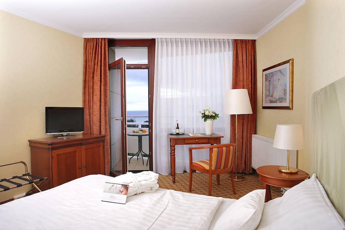 A hotel room with a bed, a desk with a chair, a television, and a view of the outdoors.