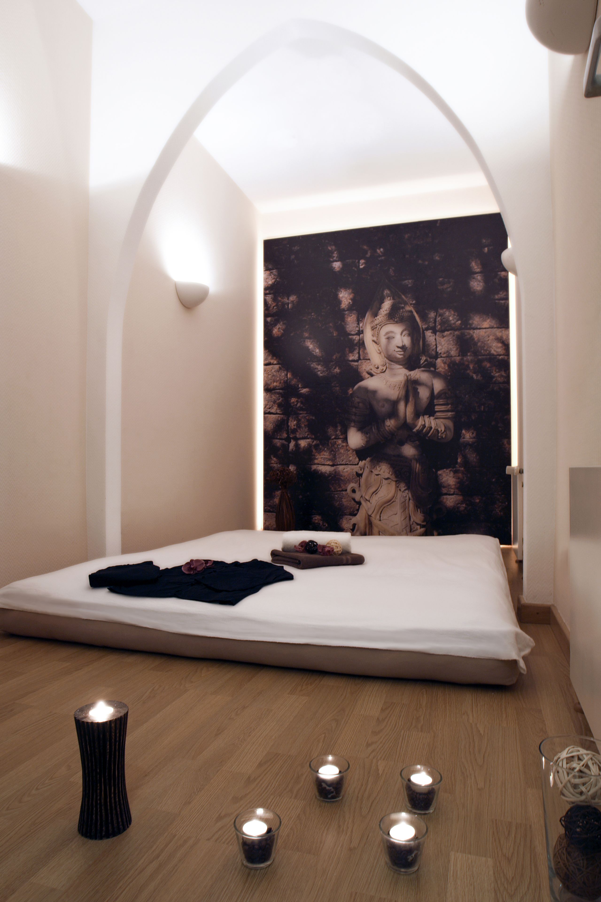 Ein Schlafzimmer mit einem Bett, Wandteppich und mehreren Kerzen auf dem Boden.