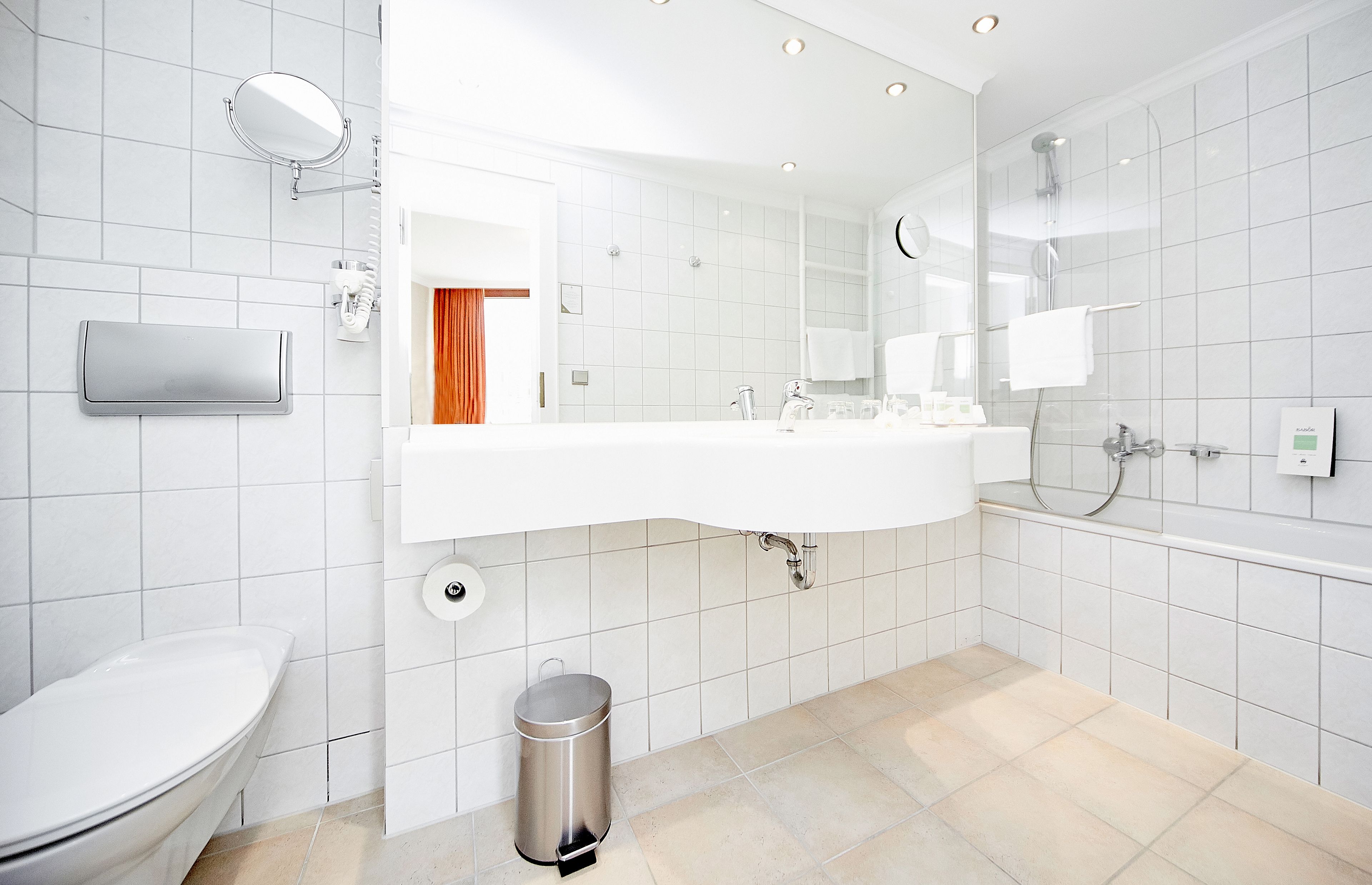 A modern bathroom with a white sink, mirror, and toilet.