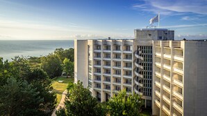 Un hôtel de grande hauteur doté de nombreux balcons, surmonté d’un drapeau et offrant une vue sur la mer.