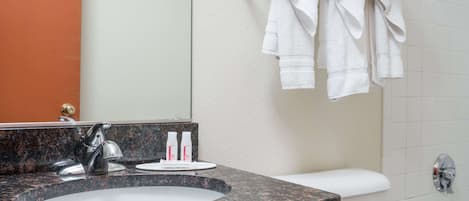 A bathroom with a granite sink, a mirror, a towel rack with towels, and toiletries on the counter.