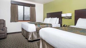 A hotel room with two beds, a chair, a window with curtains, and a wall-mounted lamp.
