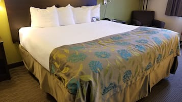 Une chambre d’hôtel avec un grand lit, une table de chevet, une lampe et une chaise.