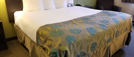 Una habitación de hotel con una cama grande, una mesita de noche, una lámpara y una silla.