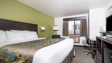 Habitación de hotel con una cama grande, un escritorio, una silla, un televisor y una ventana con cortinas.
