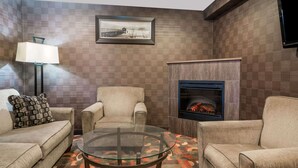 A living room with a fireplace, two armchairs, a sofa, a glass coffee table, and a lamp.
