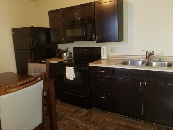 A compact kitchen with dark cabinetry, a stainless steel sink, and a built-in oven.