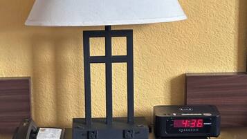 A bedside table with a lamp, a phone, and a digital clock displaying 4:36.