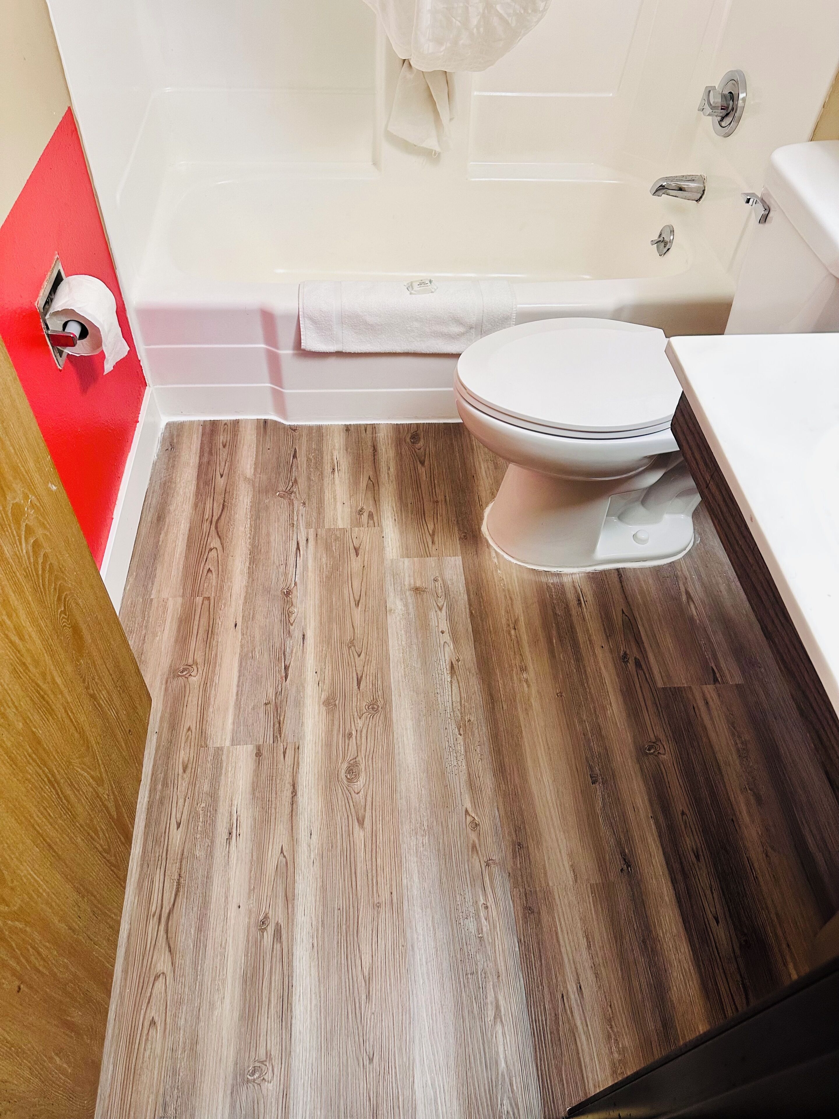 Une salle de bain avec des toilettes, une baignoire et un plancher en bois.