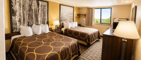 A hotel room with two beds, a desk, a chair, a lamp, and a window with a view.