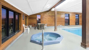 Un espacio al aire libre techado con jacuzzi, asientos y piscina.