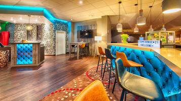 A modern bar area with a blue bar counter, multiple stools, and a television screen.