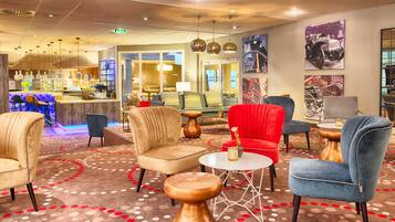 Eine Hotelhalle mit Sitzbereichen, einer Bar und Kunstwerken an den Wänden.