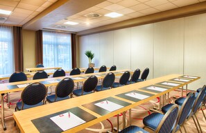 A conference room with long tables, chairs, and a potted plant. - Leonardo Hotel Mannheim - Ladenburg (Ladenburg)