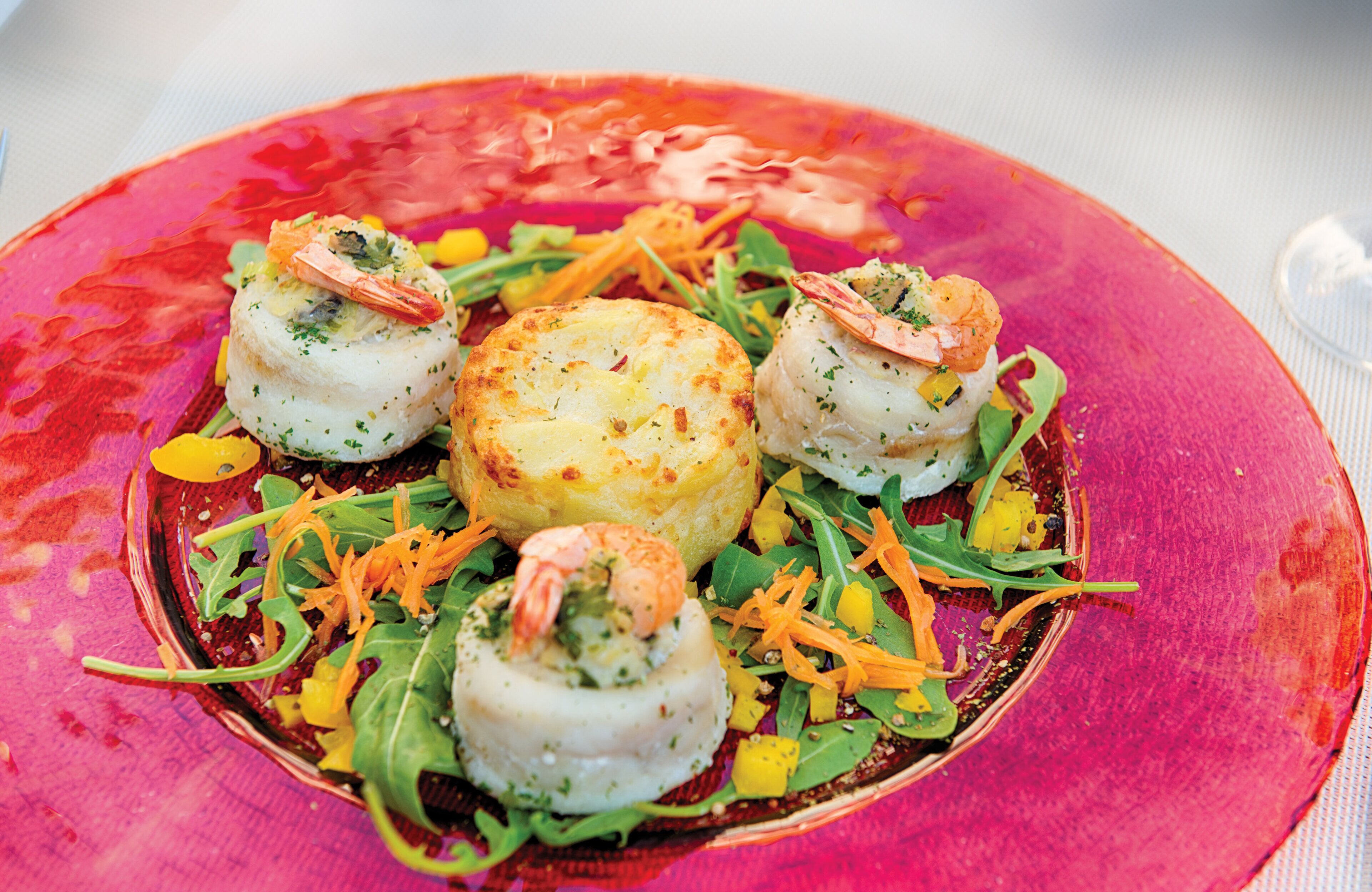 Une assiette de nourriture contenant des crevettes et un objet rond, peut-être une pâtisserie, le tout présenté sur une assiette rose vif.
