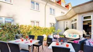 Ein Patio mit Gartenmöbeln aus Rattan, Esstische und eine Buddha-Statue.