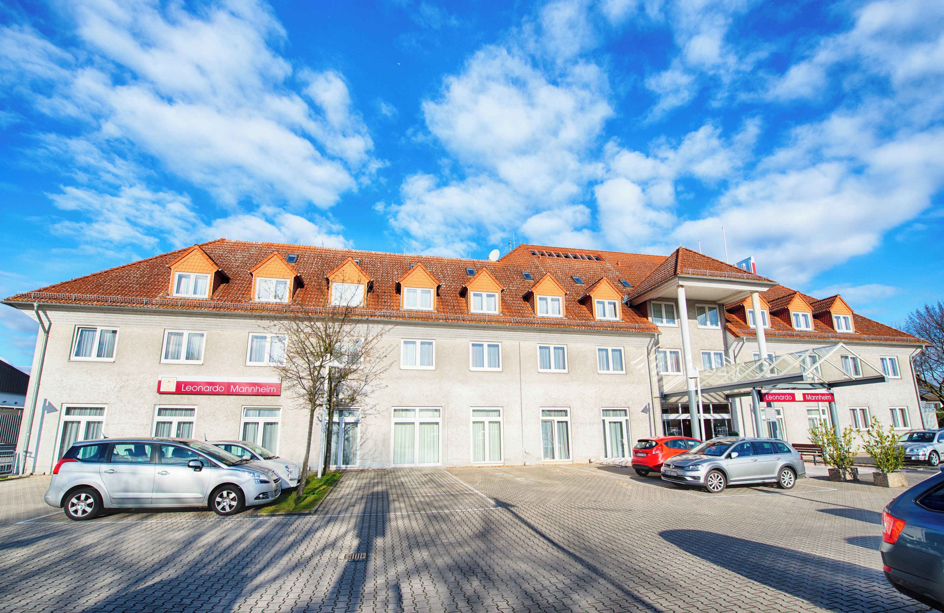 Ein Hotel mit Ziegeldach, mehreren Fenstern und einem Parkplatz mit Autos.