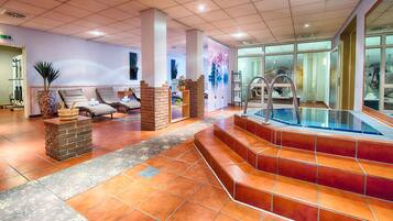 Un espacio de spa con hidromasaje, sillones reclinables y una pared de ladrillo.