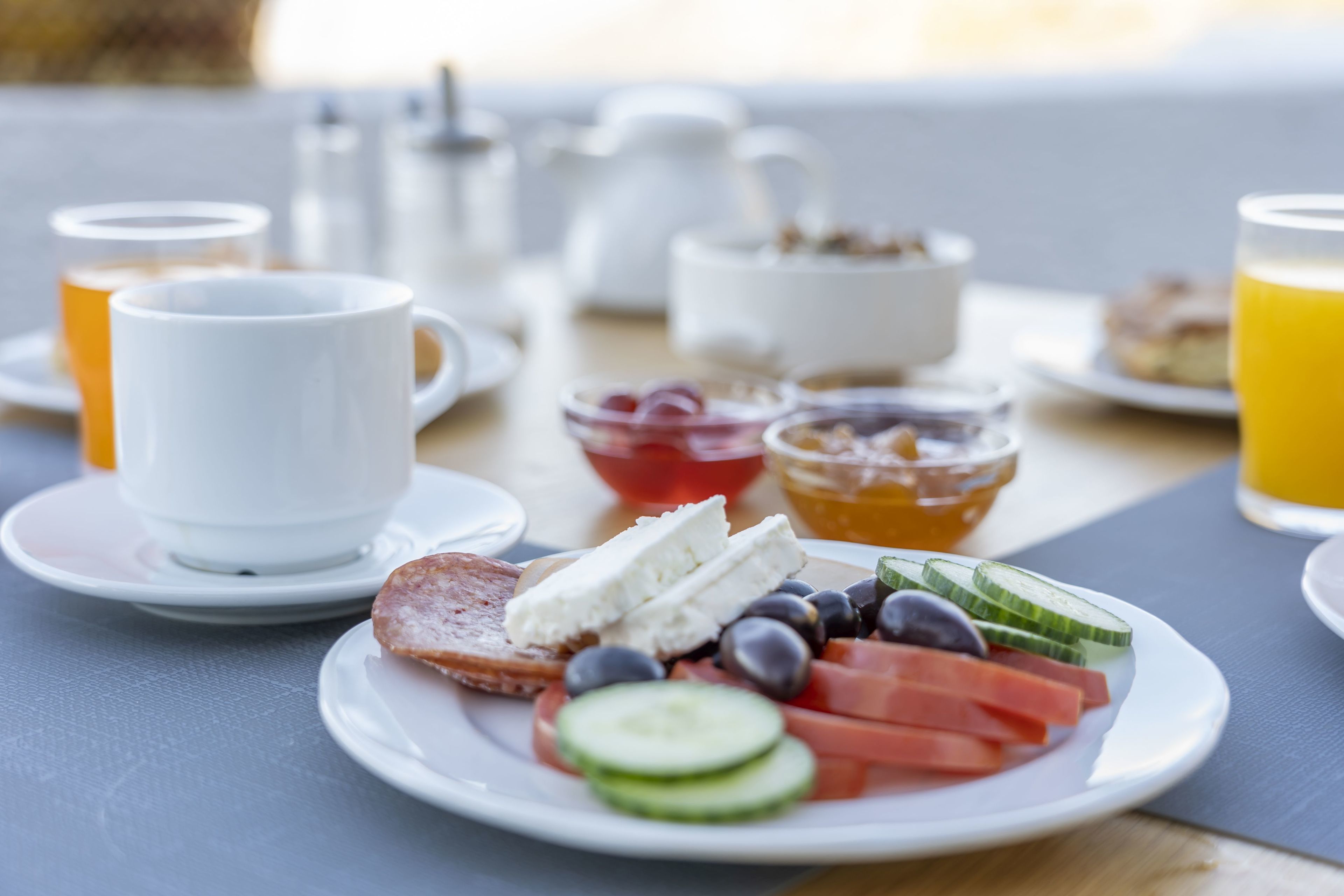 Impostazione colazione con un piatto di frutta fresca e formaggio, una tazza e un bicchiere di succo d'arancia su un tavolo.