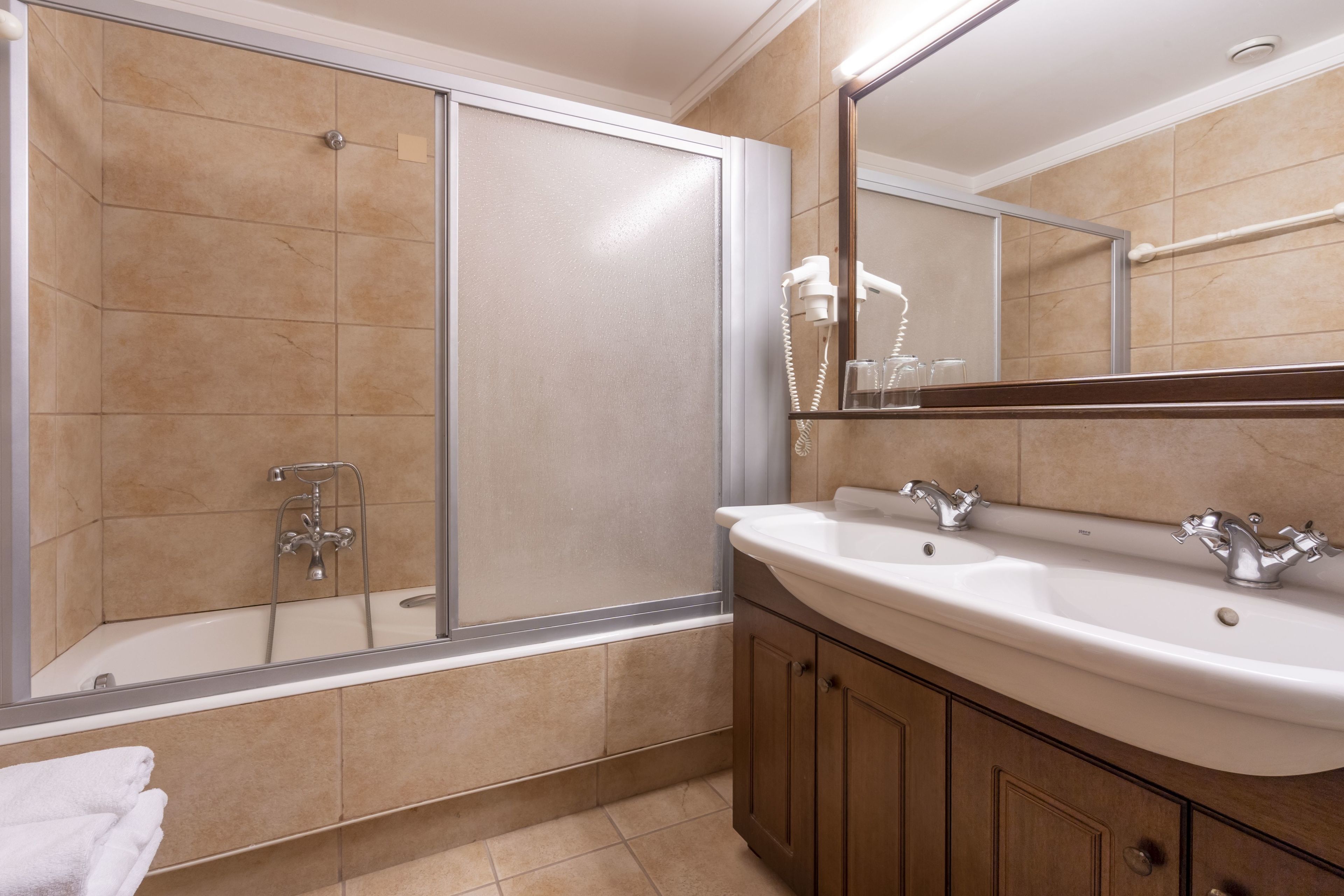 Un baño con bañera, ducha, lavamanos y espejo.