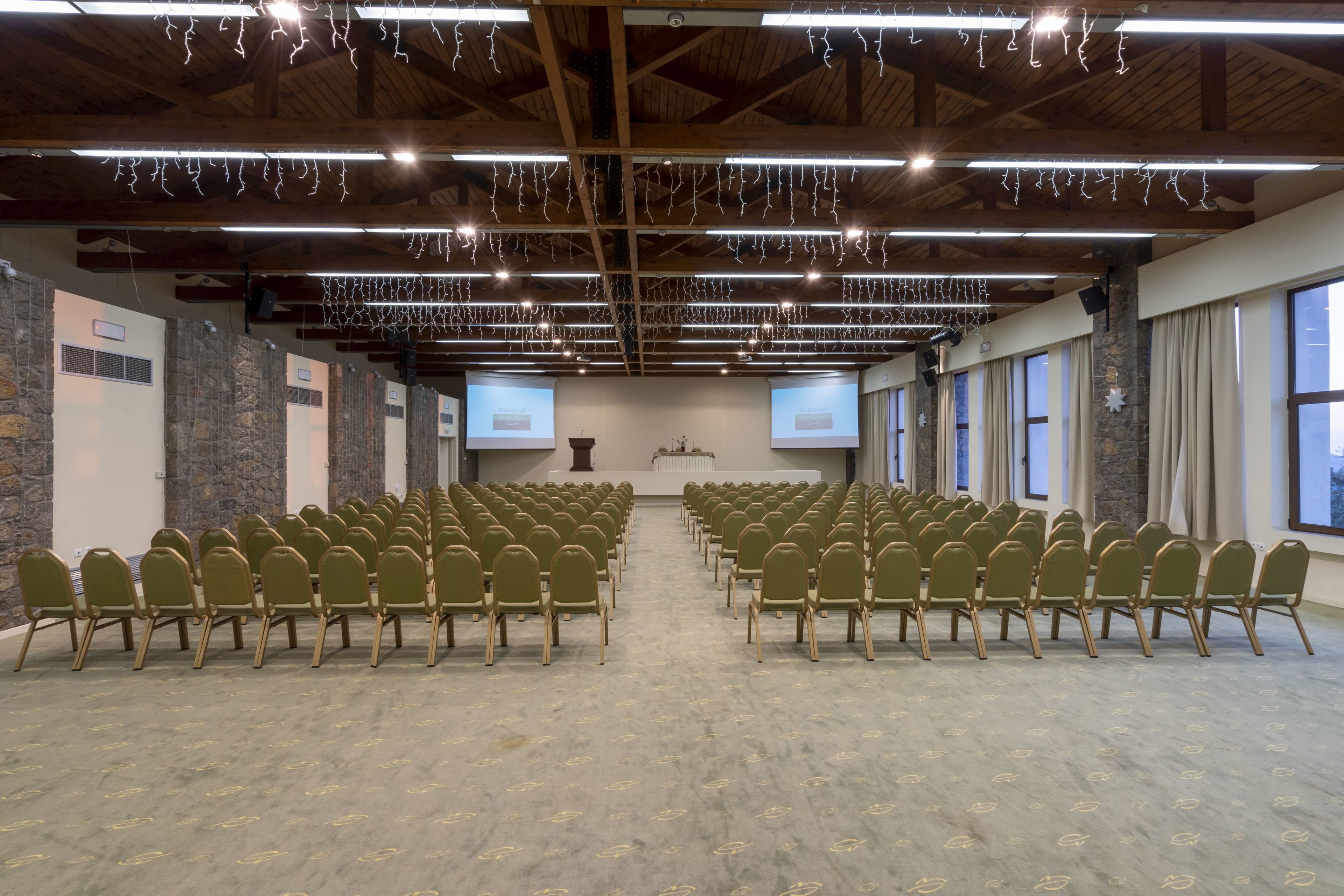 A conference room with rows of chairs, stone walls, and large windows.