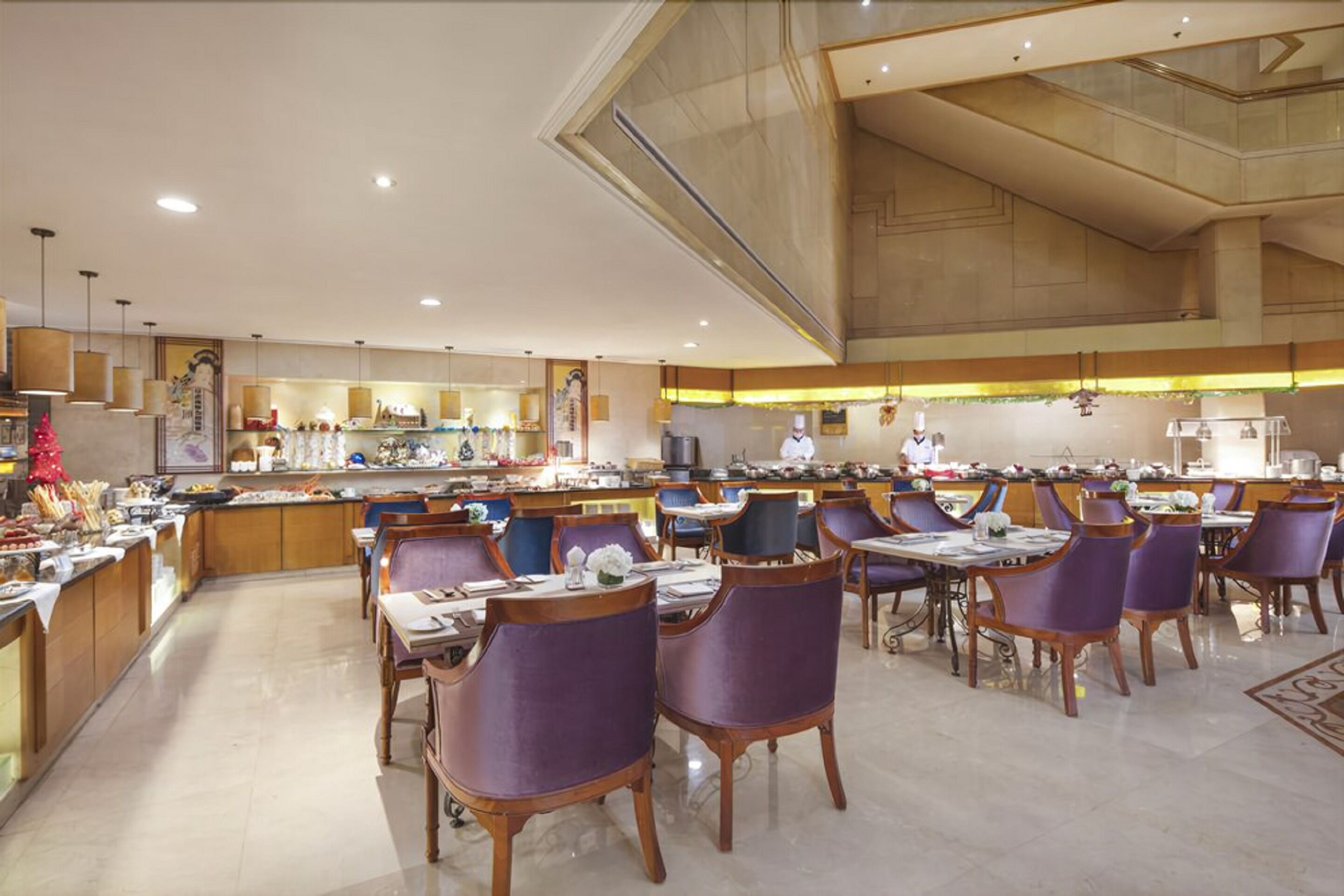 Un comedor amplio con varias mesas y sillas, una zona de bar central, y un techo alto con iluminación empotrada.