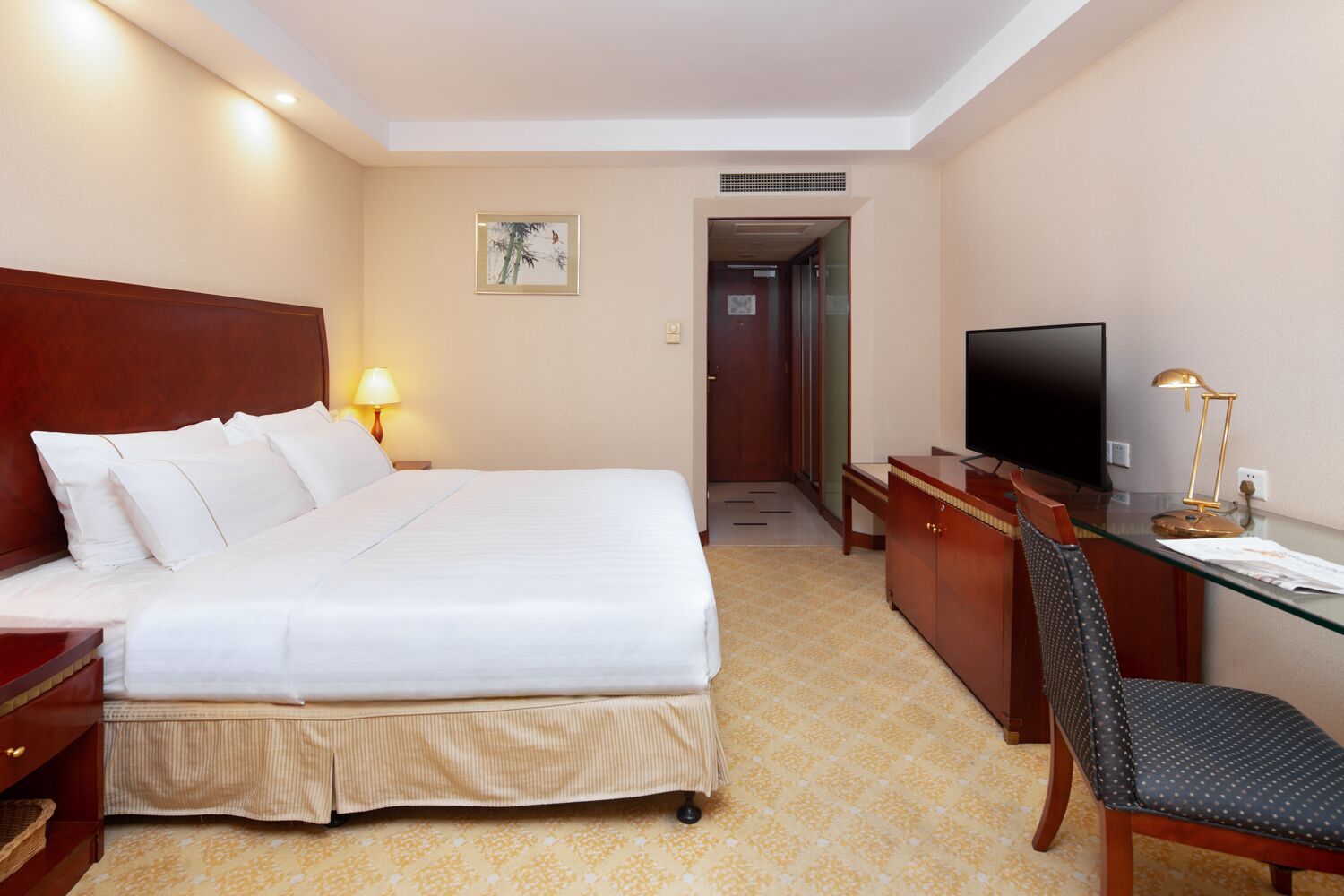 Una habitación de hotel con una cama, un escritorio, un televisor y una lámpara.