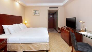 Una habitación de hotel con una cama, un escritorio, un televisor y una lámpara.
