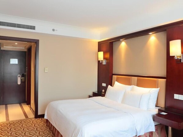 A hotel room with a large bed, a wooden headboard, two bedside tables, and a door with a handle. - Jianguo Hotel Shanghai (Shanghai)
