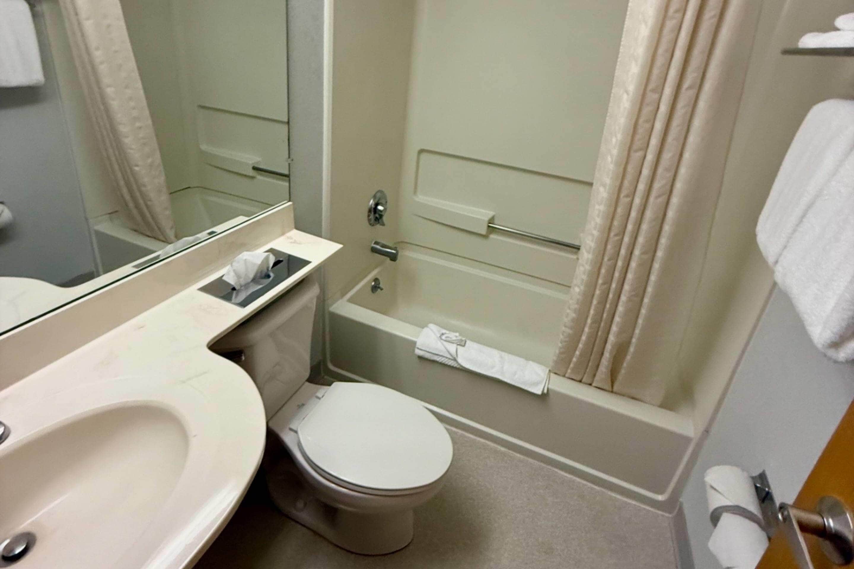 Un baño con inodoro, lavabo, bañera y espejo.