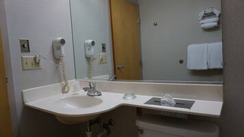 A bathroom with a sink, mirror, hairdryer, and towel rack.
