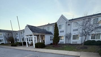 A row of residential-style buildings with a covered entryway and a small tree in the front yard.
