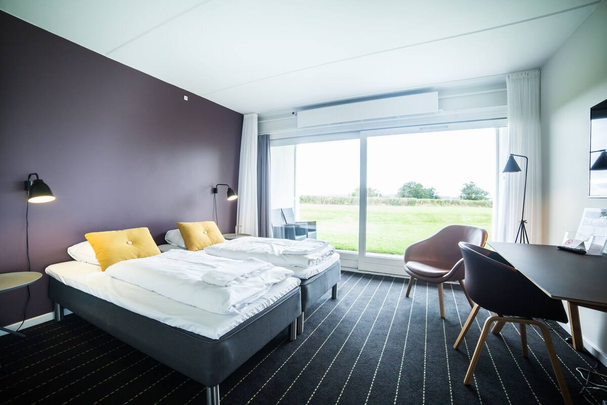 A hotel room with a bed, two bedside tables, a desk, and a chair.