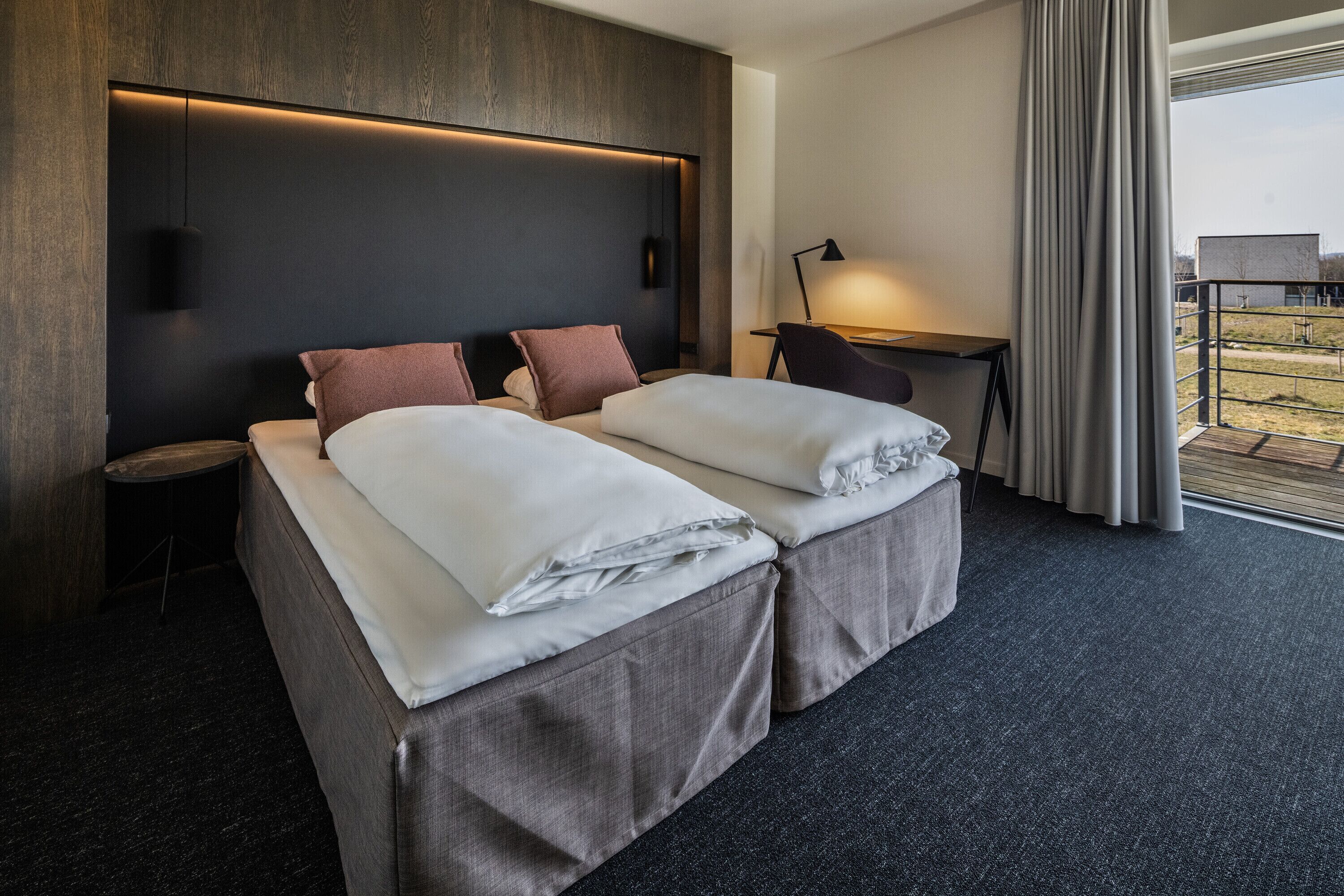 Ein modernes Hotelzimmer mit einem großen Bett, einem Schreibtisch und Blick ins Freie.