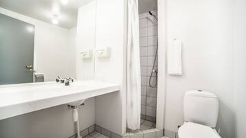 Ein modernes Badezimmer mit Waschbecken, Toilette und Dusche – alles in Weiß.