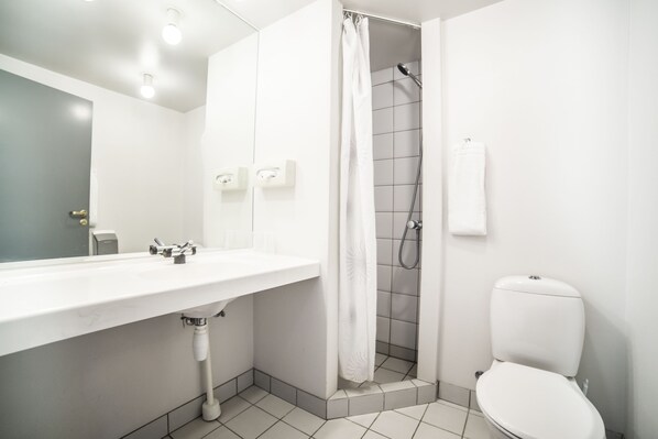 A modern bathroom with a white sink, toilet, and shower.