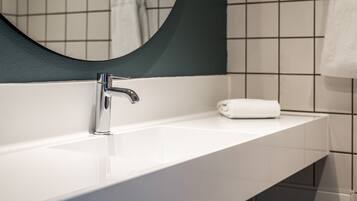 A modern bathroom with a white sink, chrome faucet, and a large mirror.