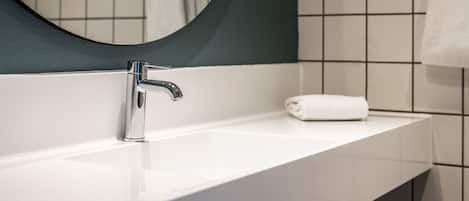 Un baño moderno con un lavamanos blanco, grifo cromado y un espejo grande.