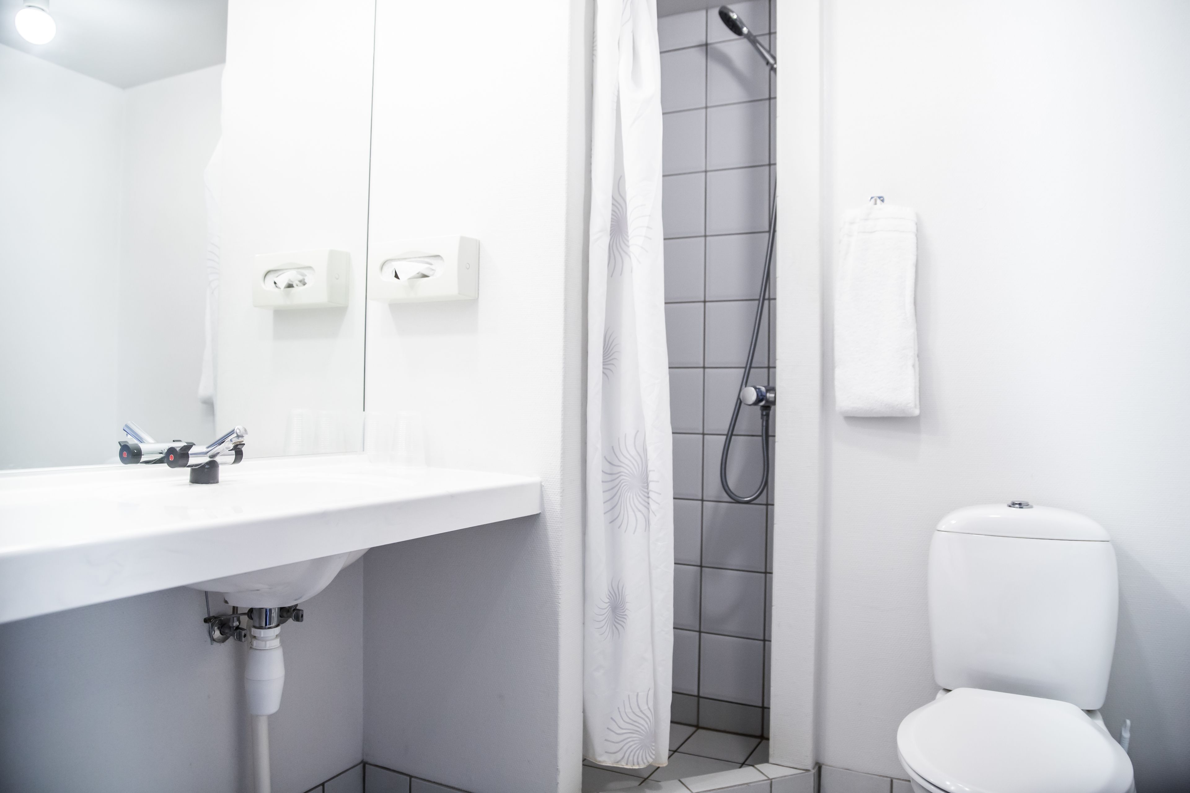 A modern bathroom with a white sink, toilet, and shower area.