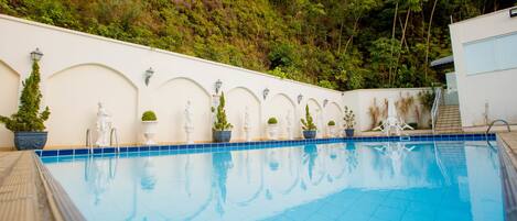 Una piscina al aire libre, sillones reclinables de piscina