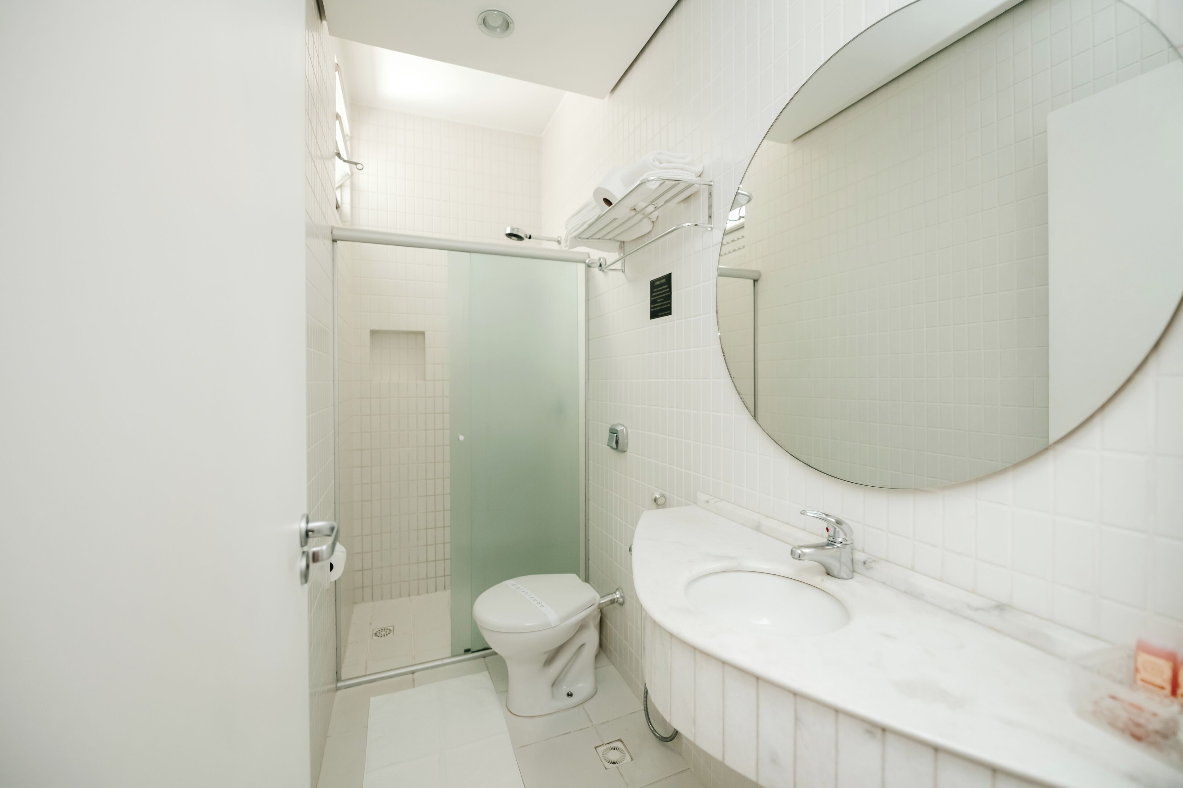 A modern bathroom with a glass shower enclosure, a white toilet, and a large mirror above a sink.