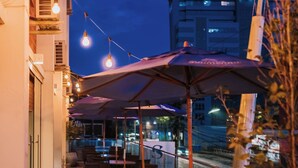 A terrace with outdoor seating, string lights, and a view of the cityscape at night. - Hotel Himmelblau (Blumenau)