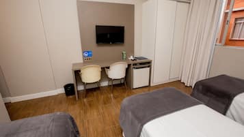 Ein Hotelzimmer mit zwei Betten, einem Schreibtisch mit Stuhl, einem Fernseher und einem Kleiderschrank.