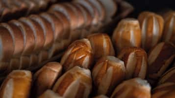 Primer plano de diferentes tipos de pan, incluyendo baguettes y bollos, con cortes visibles y una corteza dorada.